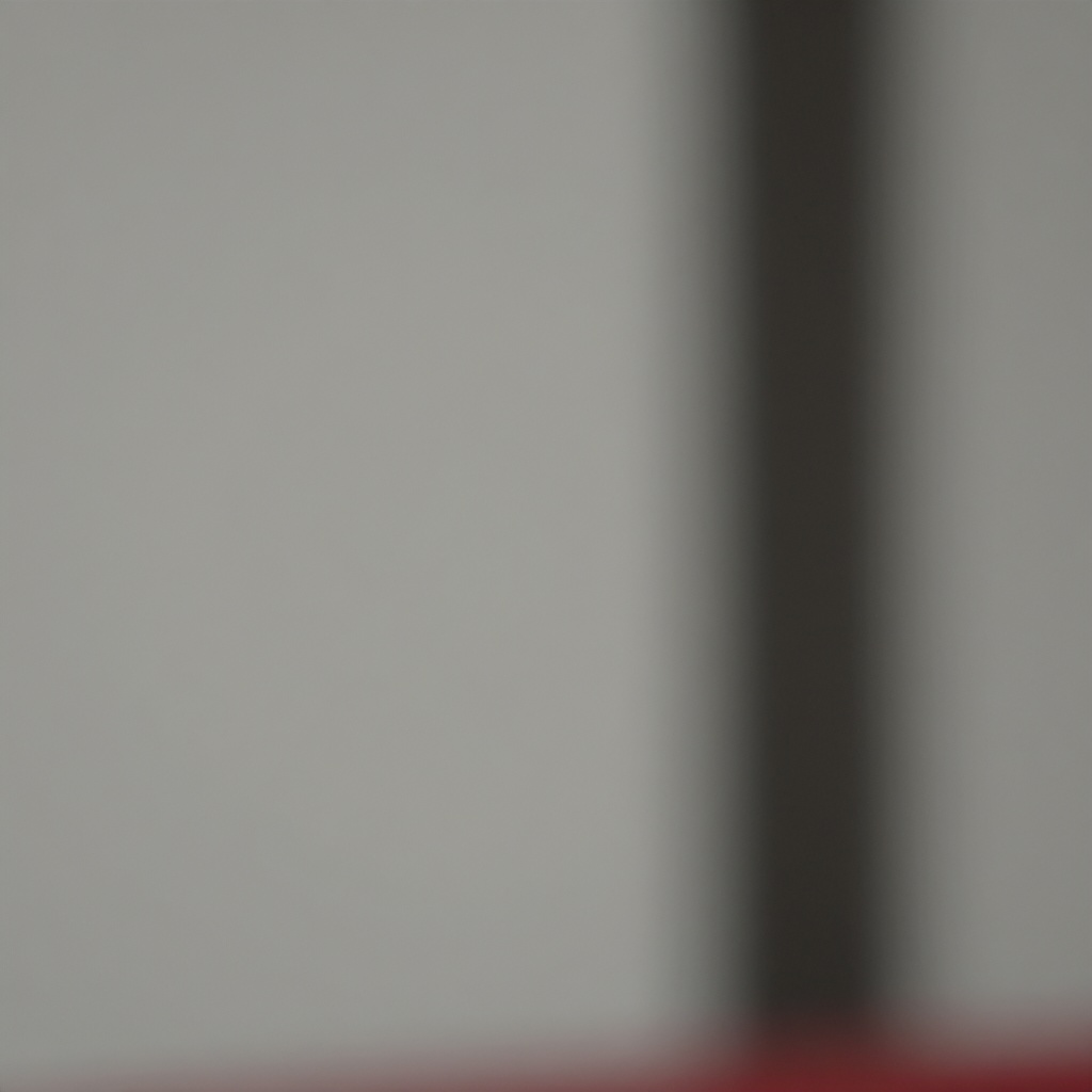 This blurry, low-resolution image features a vertical dark shape on the right side set against a pale, neutral gray background. A faint touch of red is visible at the very bottom edge of the frame. The overall composition is abstract, soft, and indistinct.