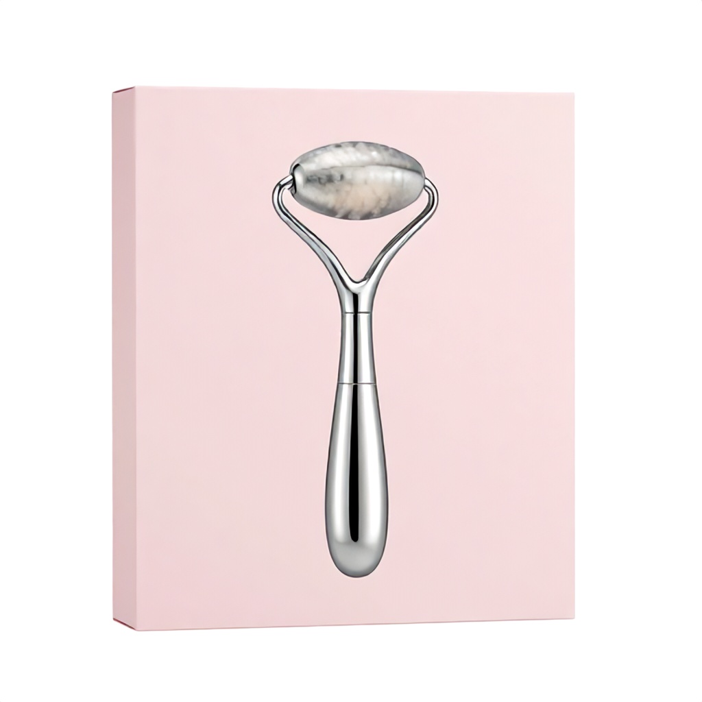 This image displays a sleek, silver-colored stainless steel facial massage tool placed in front of its light pink product packaging. The tool features a contoured, organic shape designed for ergonomic use on the face and neck. The overall presentation is clean and professional, emphasizing a modern approach to skincare tools.